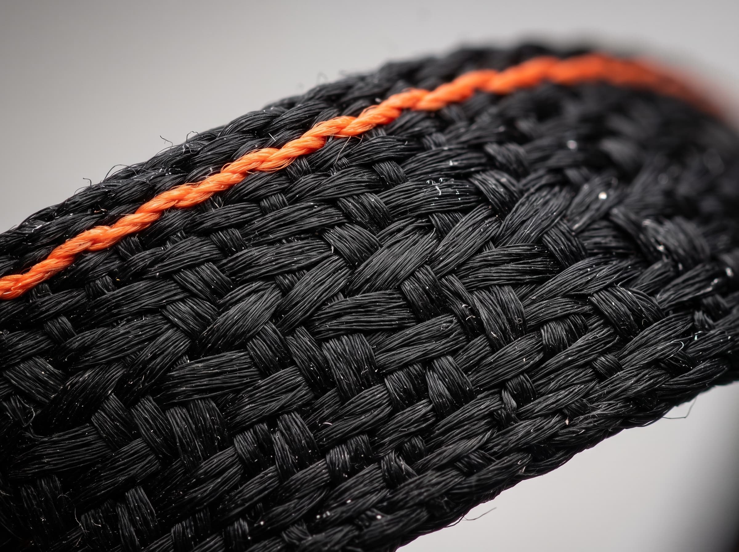 Extreme close-up of the black twill weave with a signal-orange edge thread