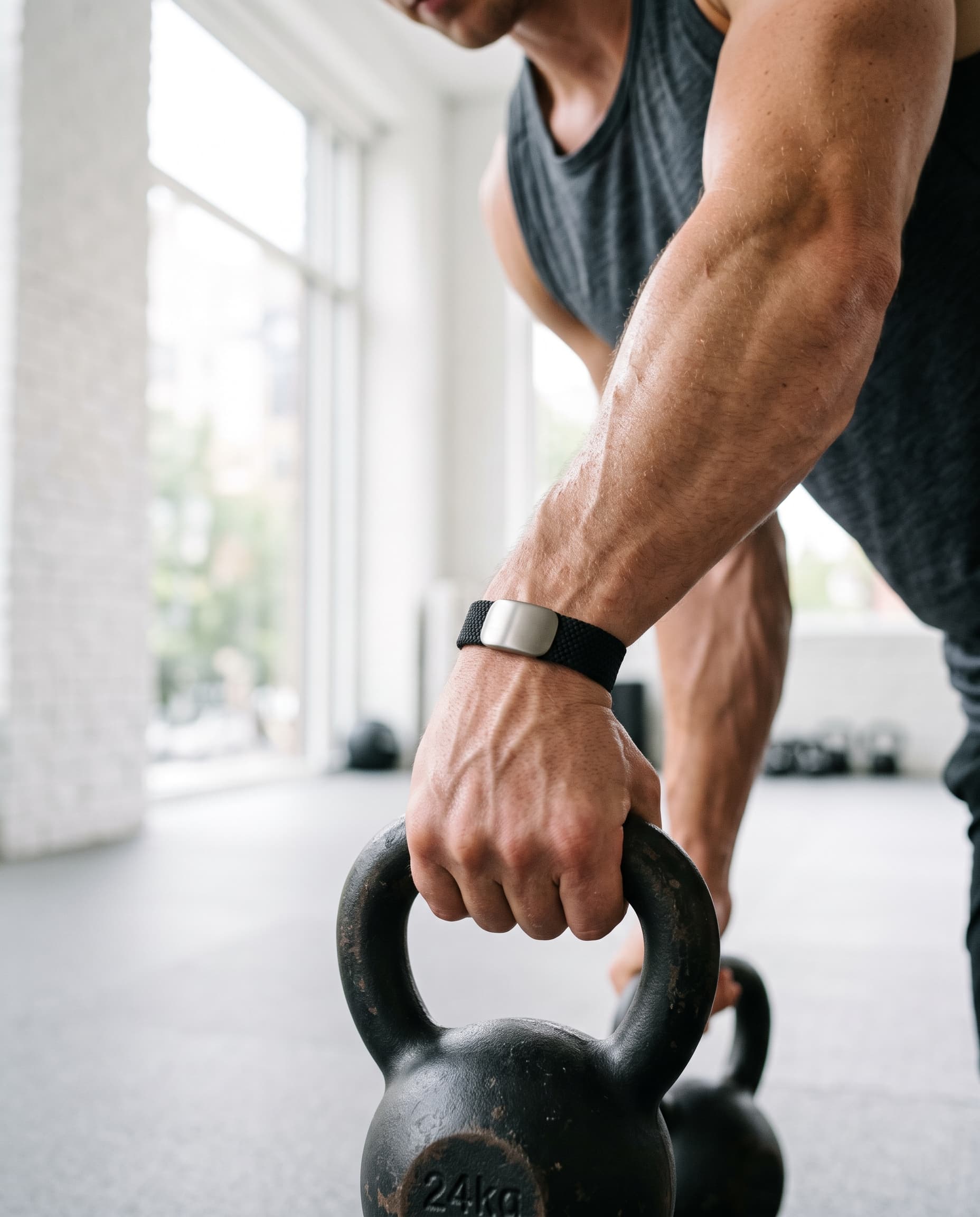 An athlete gripping a kettlebell while wearing a black PACE Band